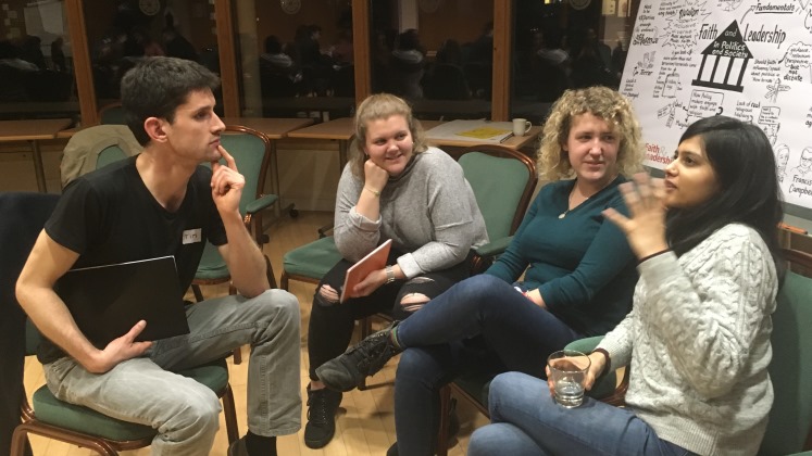 Four students, three women and a man, sitting laughing and chatting together on the Faith and Leadership residential.